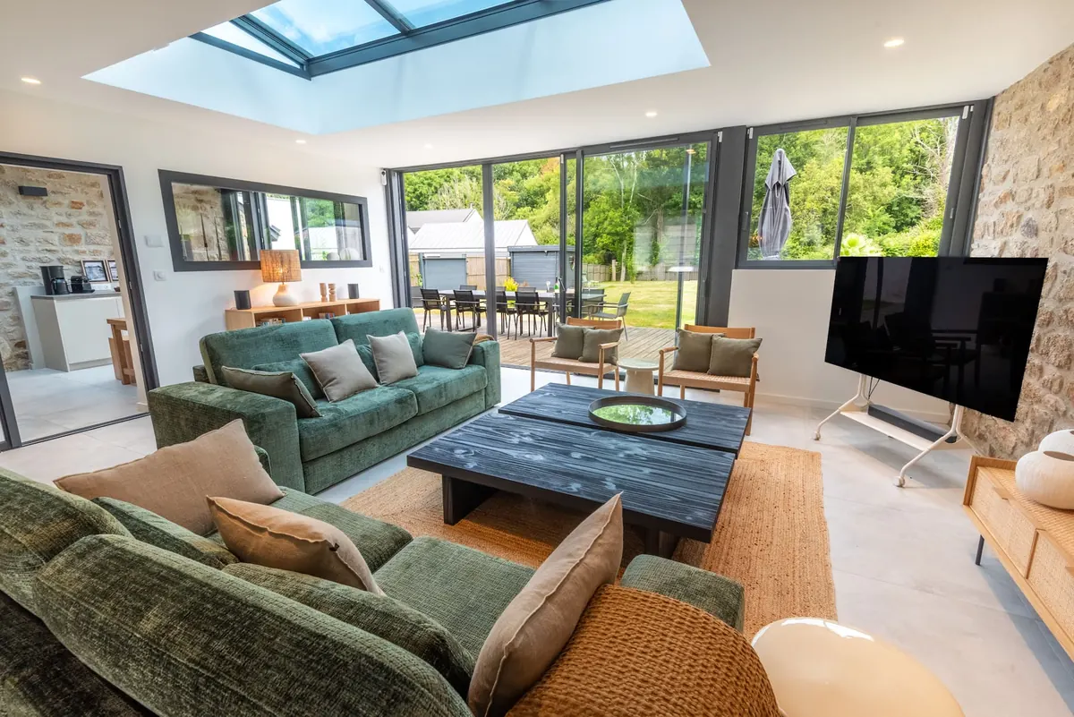 Großes Wohnzimmer unter dem Glasdach mit grünen Samtsofas