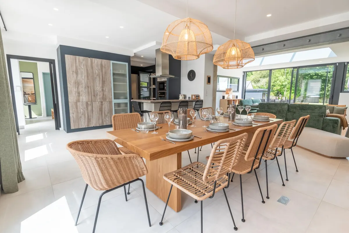 Essbereich mit großem Tisch und Rattanstühlen, offen zum Wohnzimmer